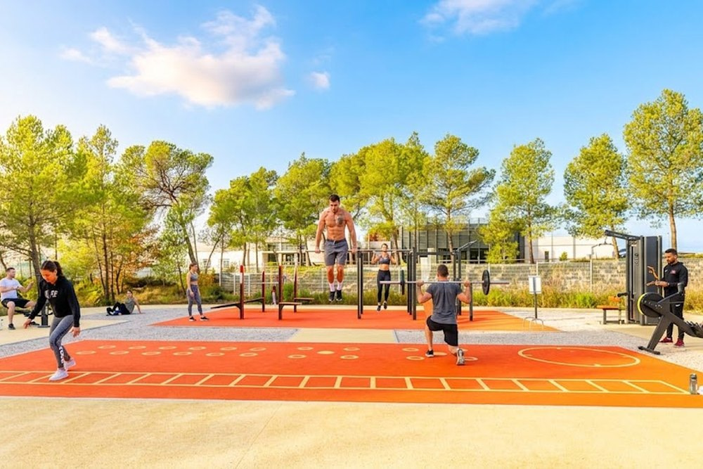 Espace de fitness et de street workout en plein air, sol sportif orange et agrès sous les pins