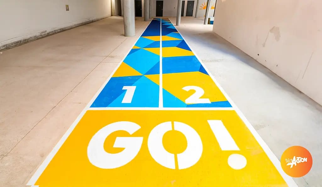 marquage-sol-groupe-scolaire-giroud-issy Piste de jeu peinte au sol dans un préau, motifs triangulaires colorés et départ marqué GO