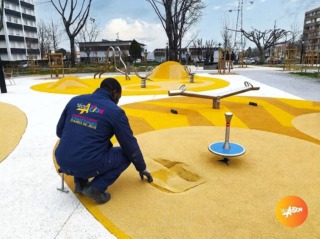 reparation-sol-souple Agent Récré'Action réparant une zone de sol souple sur une aire de jeux colorée