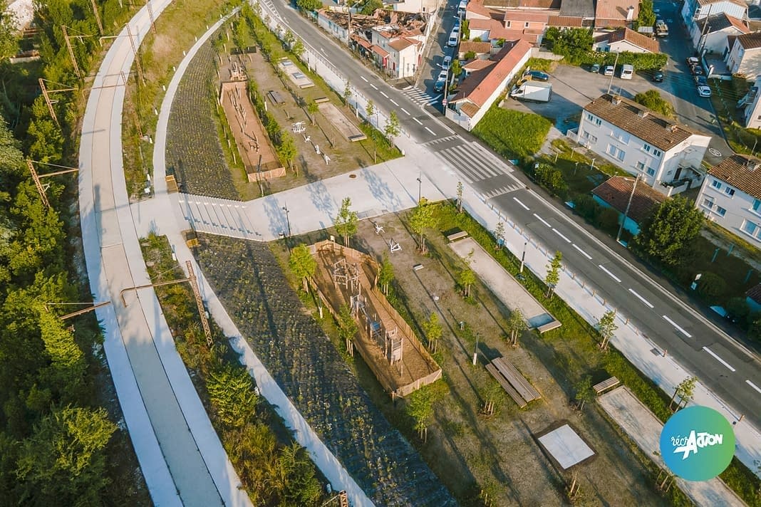 square-brazzaligne-cenon-vue-ensemble Vue aérienne d'un parc réunissant une aire de jeux en bois et une ligne d'agrès de fitness, en bord de rue
